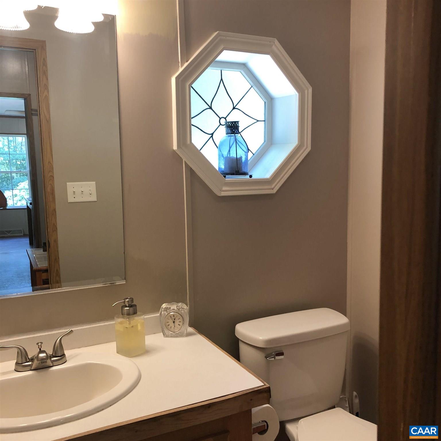 583 Rippin Run Road Ruckersville, VA 22968 - Photo 16 of 28 a bathroom with a sink a mirror a toilet and a window