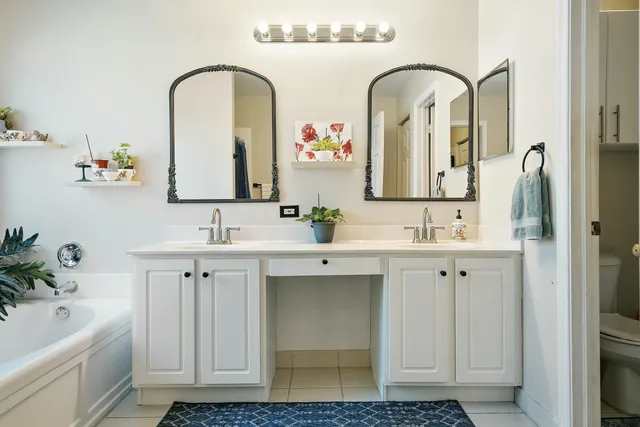 a bathroom with a double vanity sink mirror and bathtub