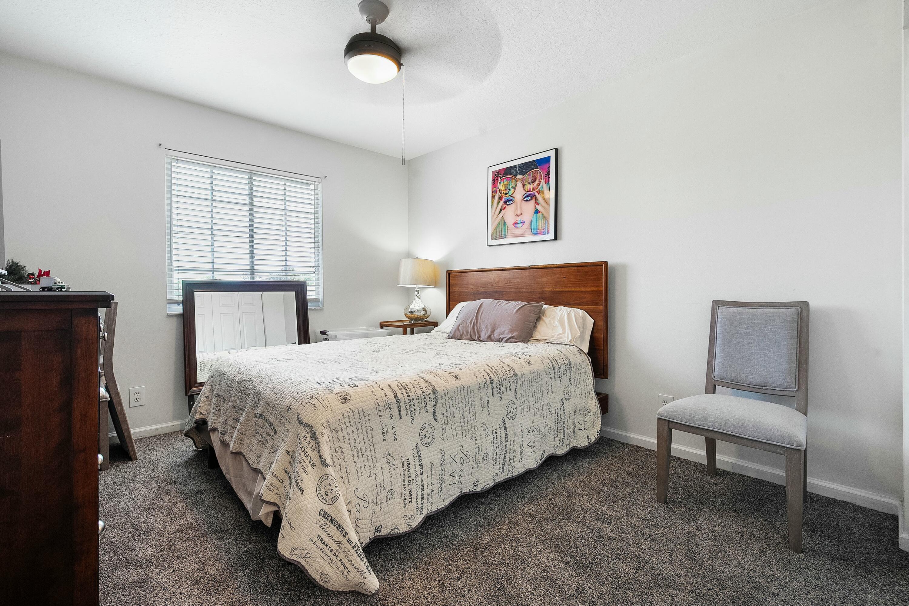 2480 Southeast Springtree Place Stuart, FL 34997 - Photo 27 of 39 a bedroom with a bed and a chandelier