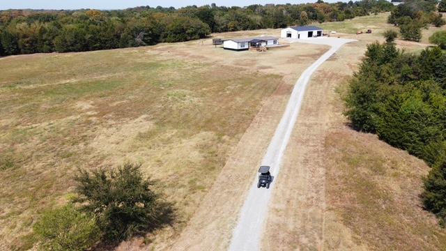 36469 1330th Road Wewoka, OK 74884 - Photo 6 of 39 Expansive rural property featuring a gravel driveway, a single-story residence, and a separate outbuilding, all surrounded by open land and mature trees