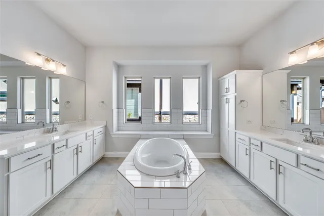 a large bathroom with a double vanity sink a large mirror and a bathtub