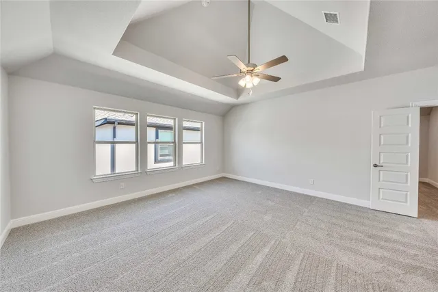 an empty room with chandelier fan and windows