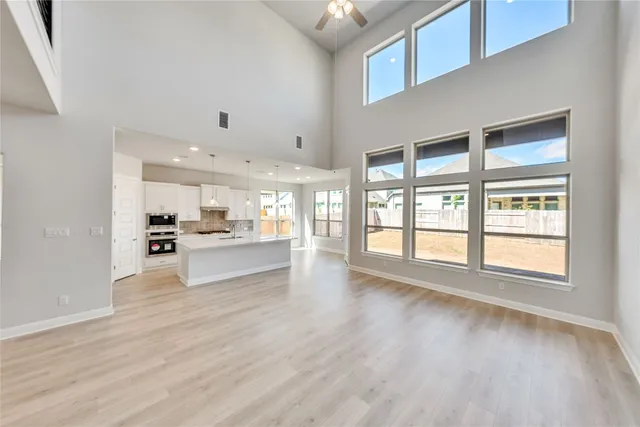a view of an empty room with kitchen view and a window