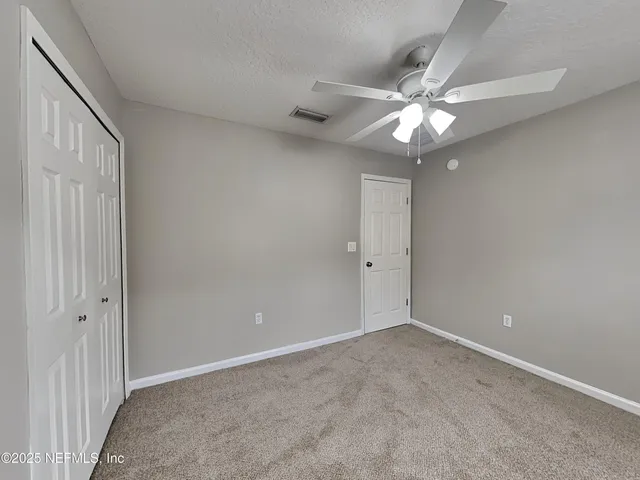 a view of an empty room with a chandelier fan