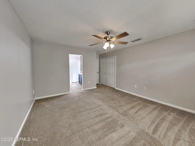 a view of an empty room with a chandelier fan