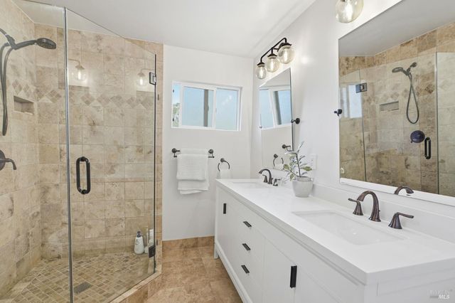 a bathroom with a double vanity sink mirror and shower