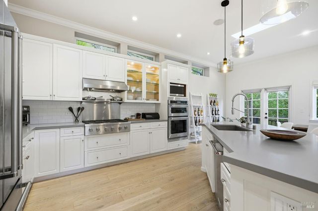 a kitchen with kitchen island granite countertop a sink counter top space appliances and cabinets