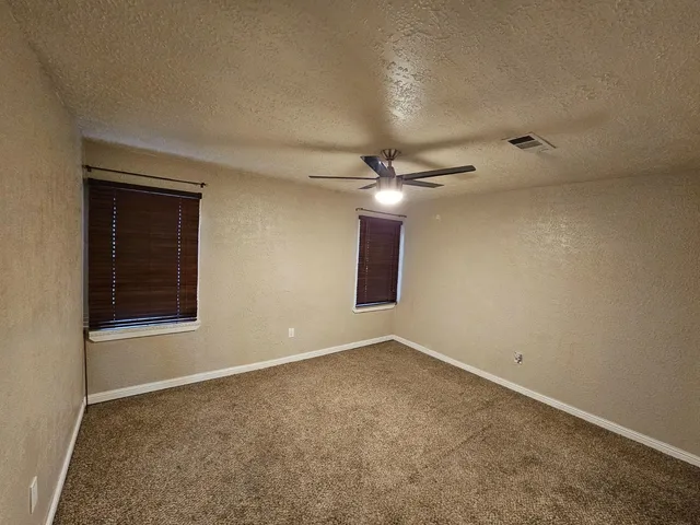 an empty room with a ceiling fan and a window