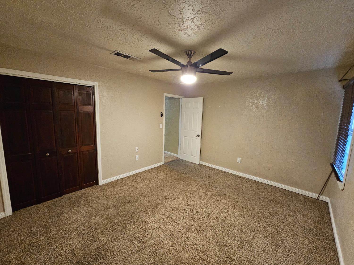 1140 Locust Street Gridley, CA 95948 - Photo 12 of 22 an empty room with a ceiling fan and a window