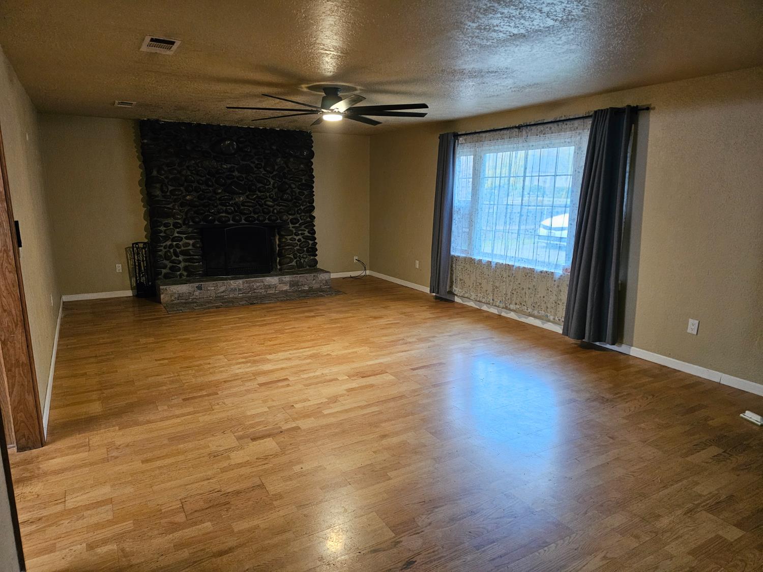 1140 Locust Street Gridley, CA 95948 - Photo 3 of 22 an empty room with wooden floor and fireplace