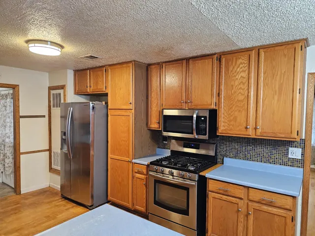 a kitchen with stainless steel appliances granite countertop a refrigerator stove and microwave