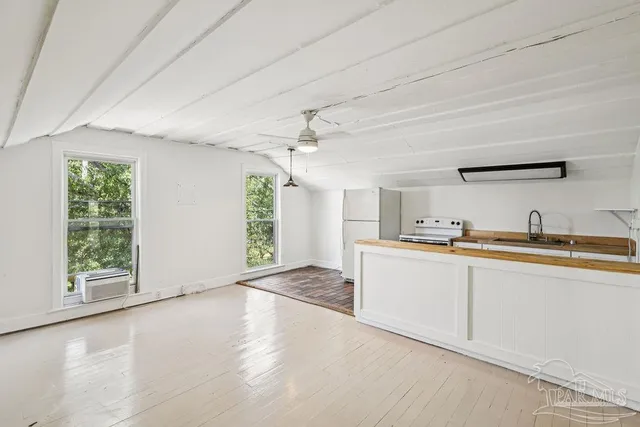 a large white kitchen with granite countertop a large window and a sink