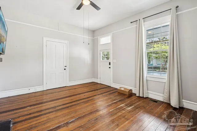 a view of an empty room with wooden floor and a window