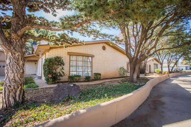 a front view of a house with a garden and trees