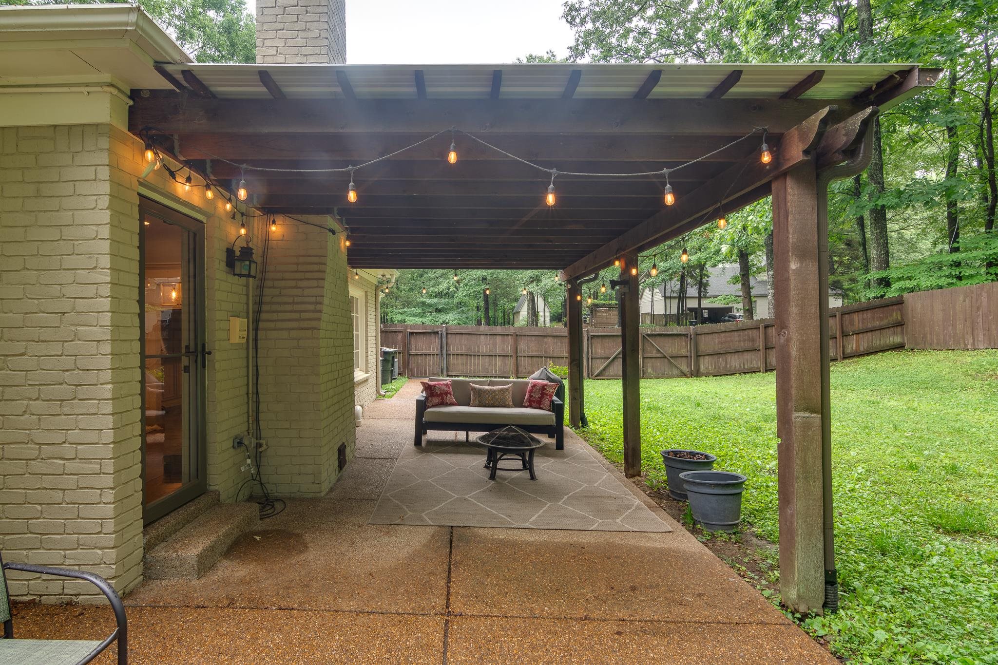 791 North Tree Drive Collierville, TN 38017 - Photo 24 of 27 Covered patio featuring string lighting, a concrete patio surface, and a sloped lawn area