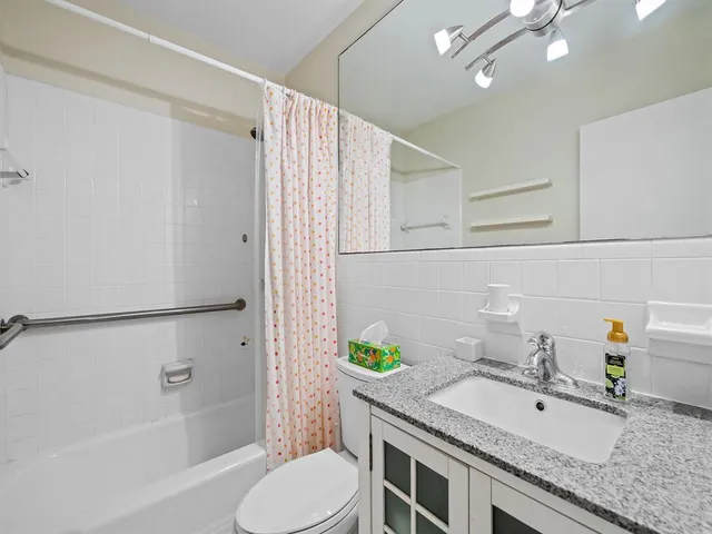 a bathroom with a granite countertop sink toilet and shower