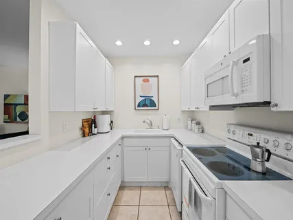 a kitchen with a sink dishwasher and white cabinets with wooden floor
