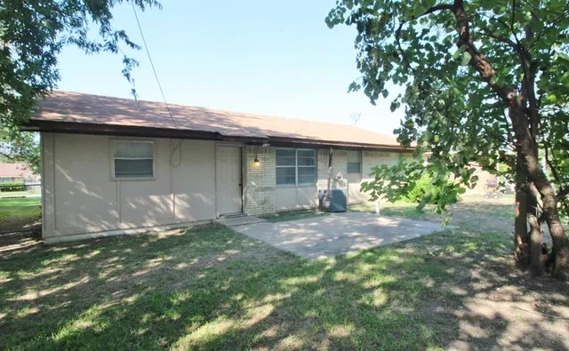 a backyard of a house with table and chairs under an umbrella