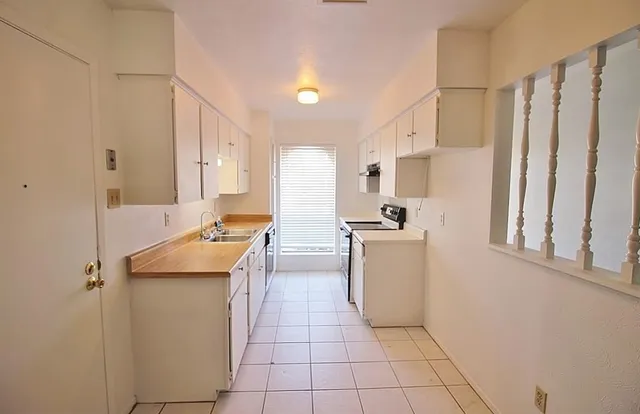 a kitchen with a sink a stove top oven and cabinets