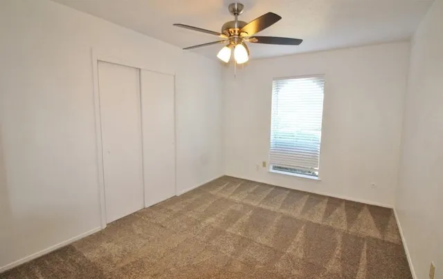 an empty room with windows and fan