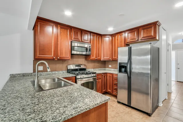 a kitchen with stainless steel appliances granite countertop a refrigerator a stove top oven a sink and dishwasher