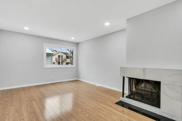 a view of an empty room with wooden floor and a fireplace