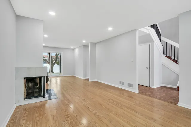 a view of an empty room with wooden floor and a fireplace