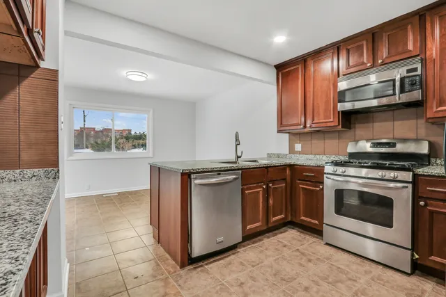 a kitchen with stainless steel appliances granite countertop a stove a sink and a microwave