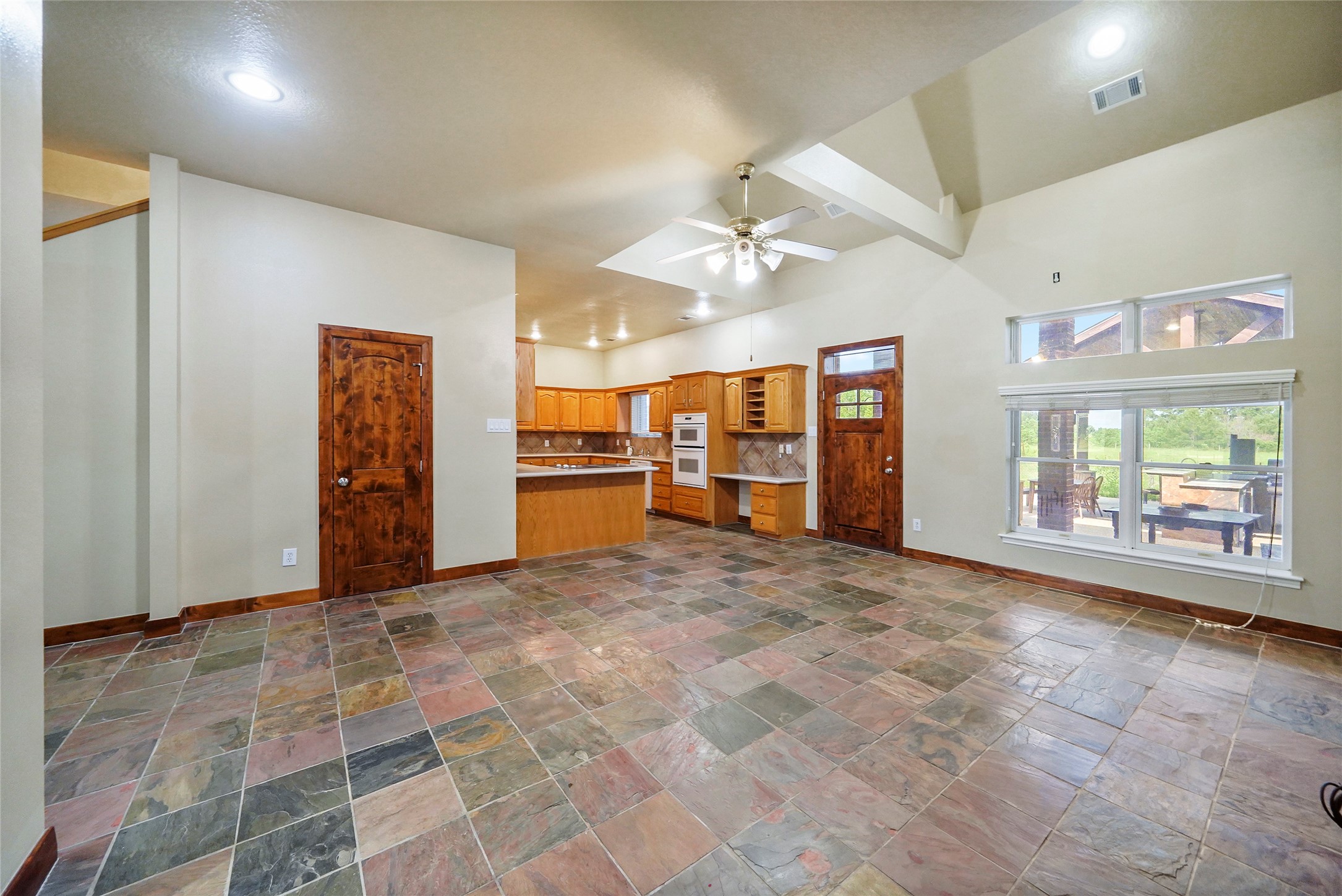 19250 Becker Road Hockley, TX 77447 - Photo 17 of 38 Open living area with soaring ceilings and slate flooring, leading into the kitchen.