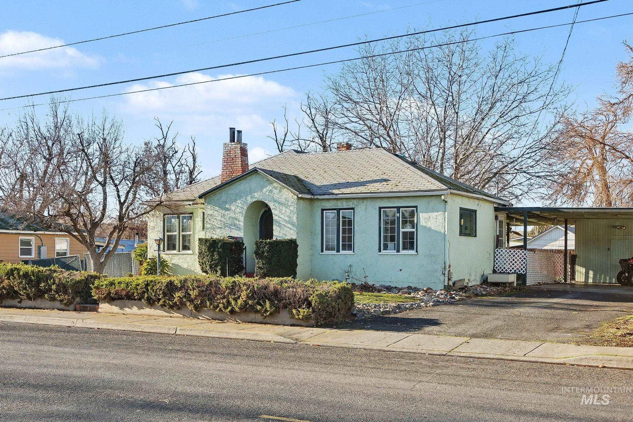 View of front of house with stucco siding, a chimney, asphalt driveway, roof with shingles, and an attached carport