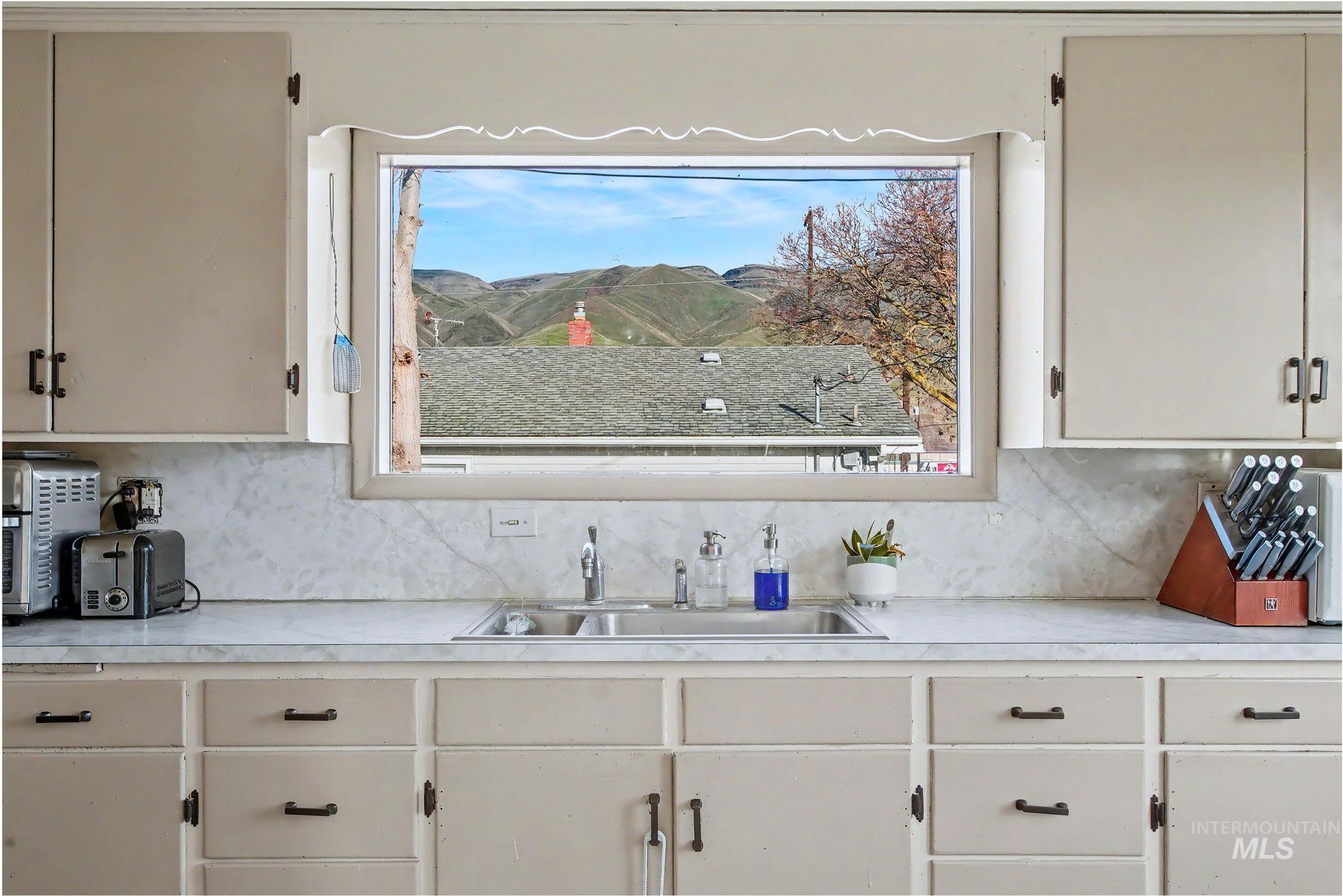 408 13th Street Clarkston, WA 99403 - Photo 10 of 34 Kitchen featuring light countertops, backsplash, and white cabinetry