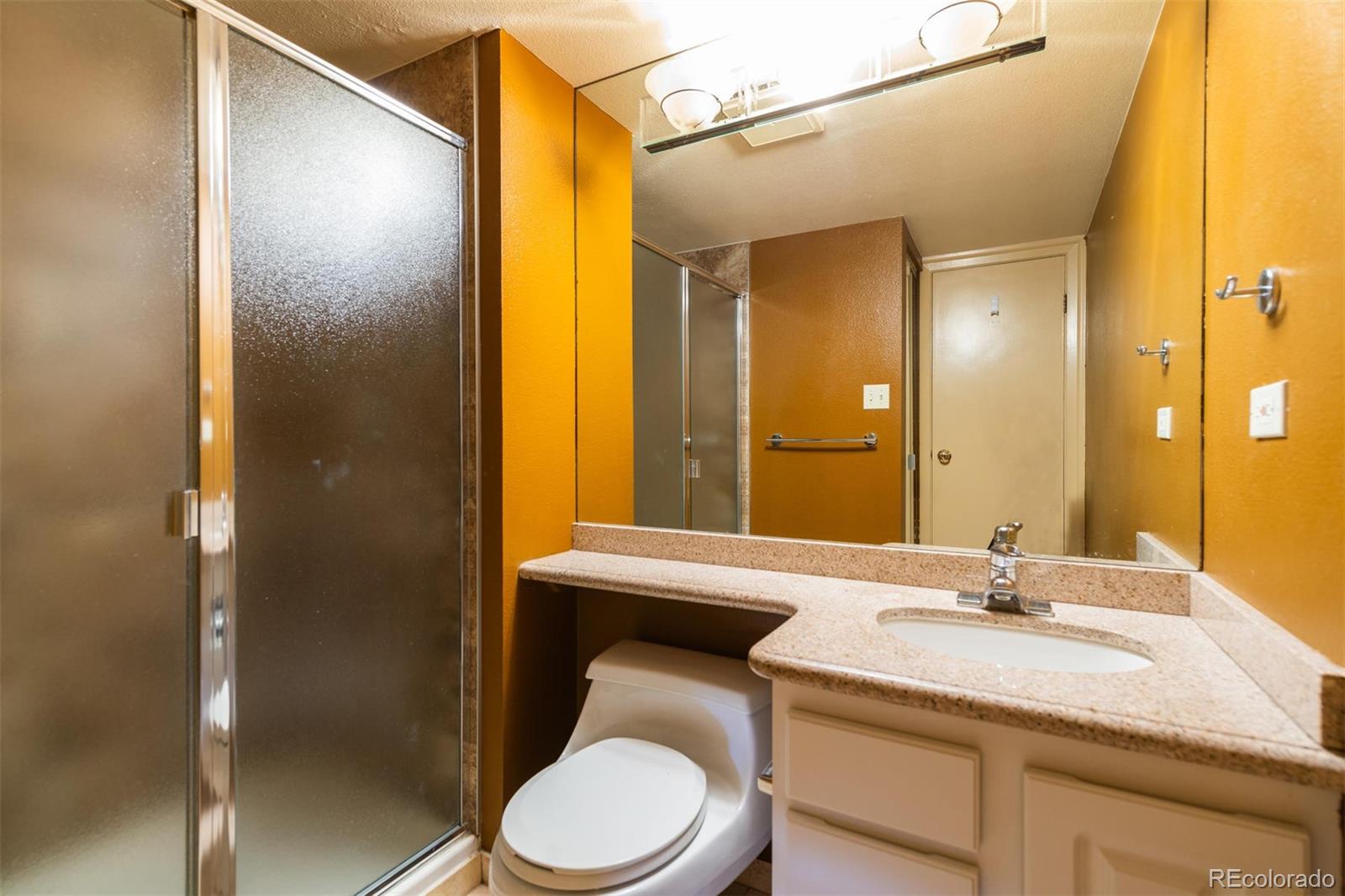 1313 North Williams Street, Unit 906 Denver, CO 80218 - Photo 18 of 31 a bathroom with a granite countertop sink toilet a mirror and shower