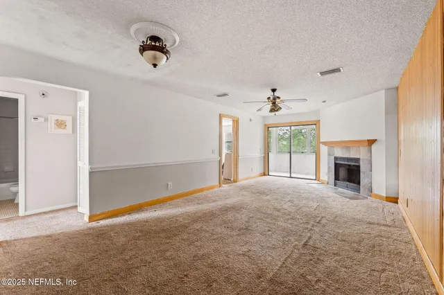 an empty room with windows and fireplace