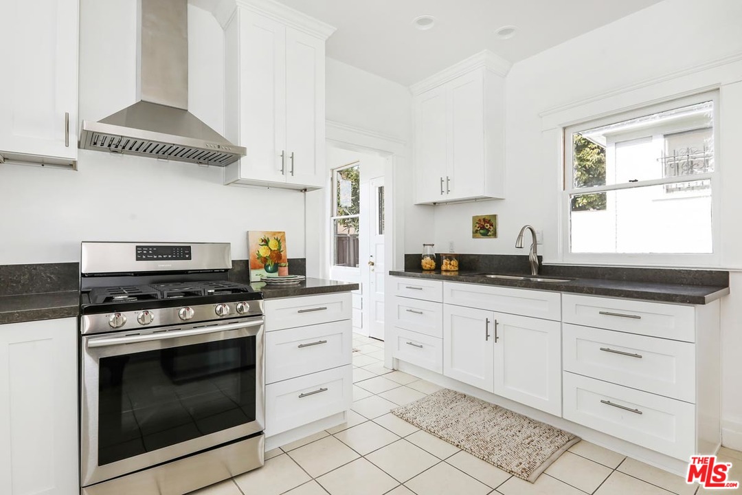 755 East Kensington Road Los Angeles, CA 90026 - Photo 10 of 25 a kitchen with white cabinets stainless steel appliances and a window