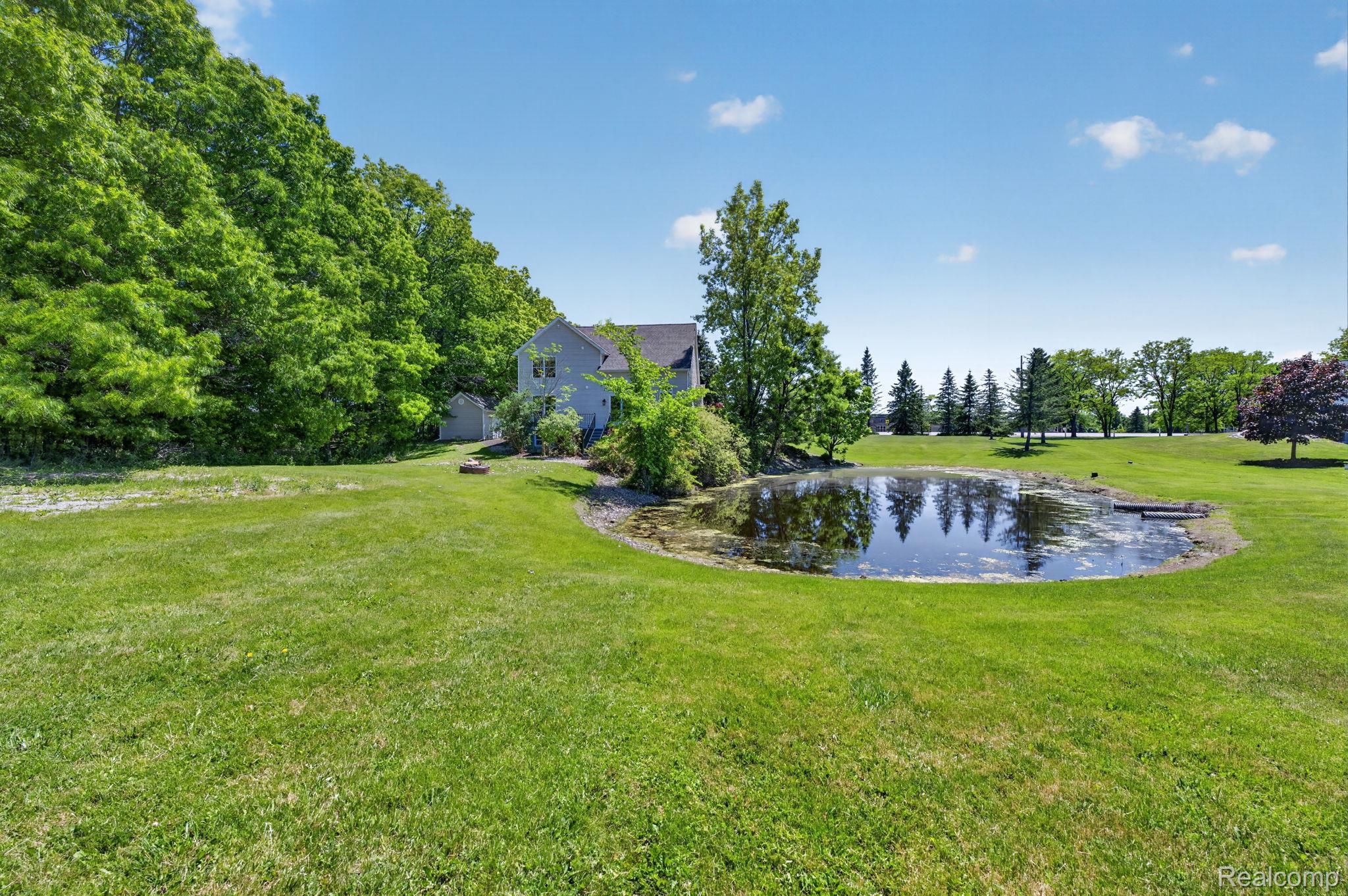 9055 Hegel Road Grand Blanc, MI 48439 - Photo 8 of 62 Expansive grounds featuring a private pond with a small dock, surrounded by mature trees and manicured lawns