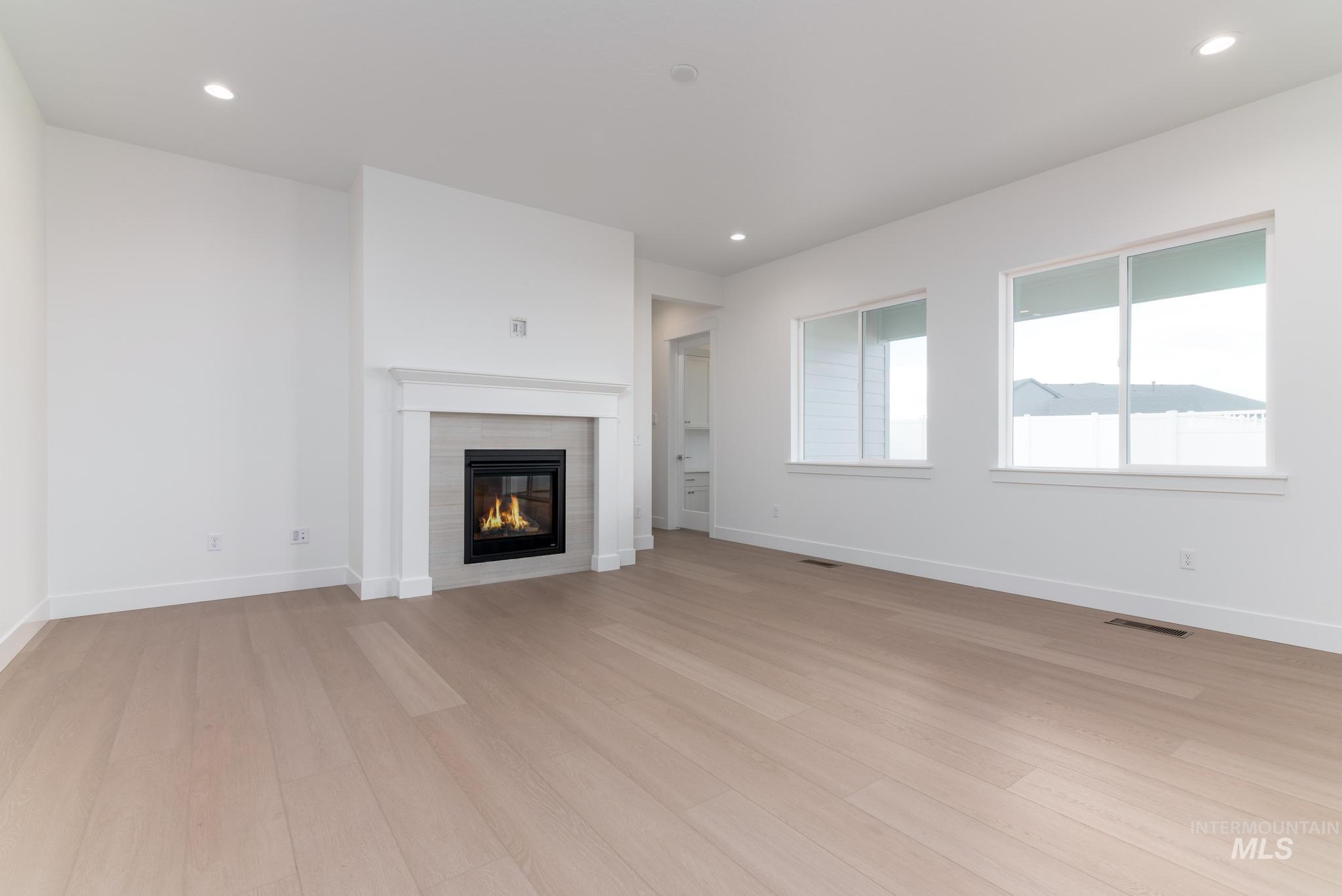 8501 South Country Wind Avenue Meridian, ID 83642 - Photo 5 of 38 Unfurnished living room featuring light wood-style floors, recessed lighting, and a fireplace