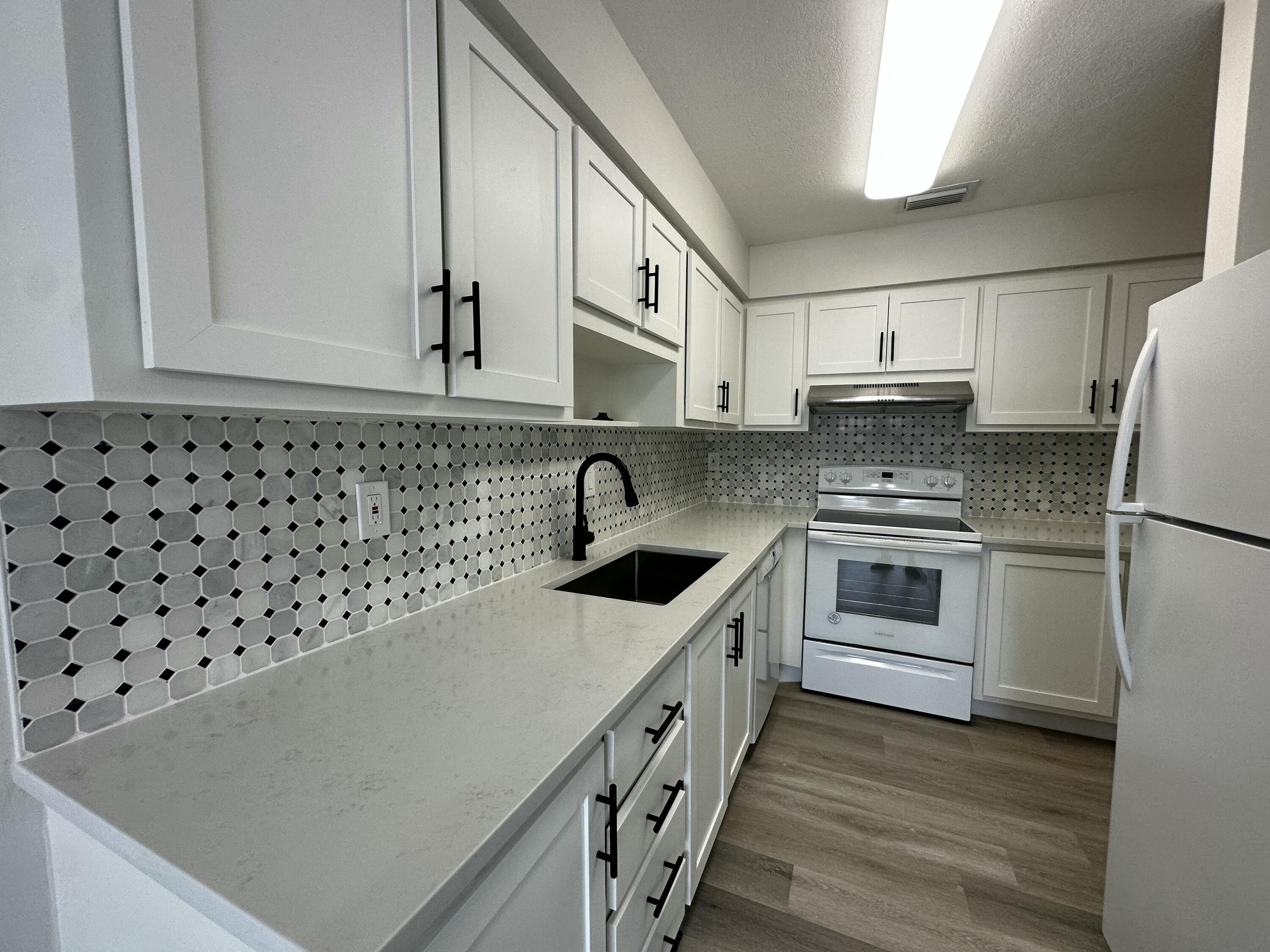13682 Vía Flora, Unit H Delray Beach, FL 33484 - Photo 11 of 28 a kitchen with granite countertop a white cabinets and white appliances