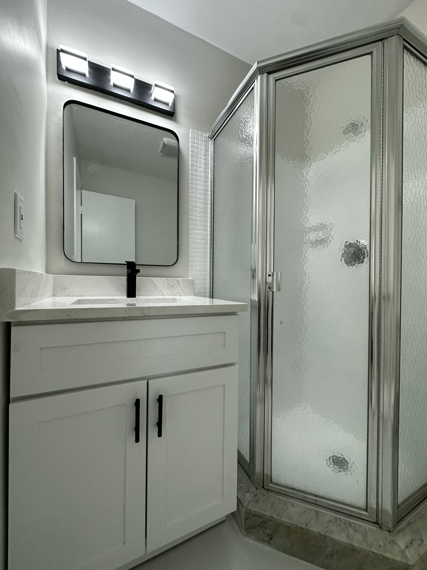 13682 Vía Flora, Unit H Delray Beach, FL 33484 - Photo 27 of 28 a bathroom with a shower sink and mirror