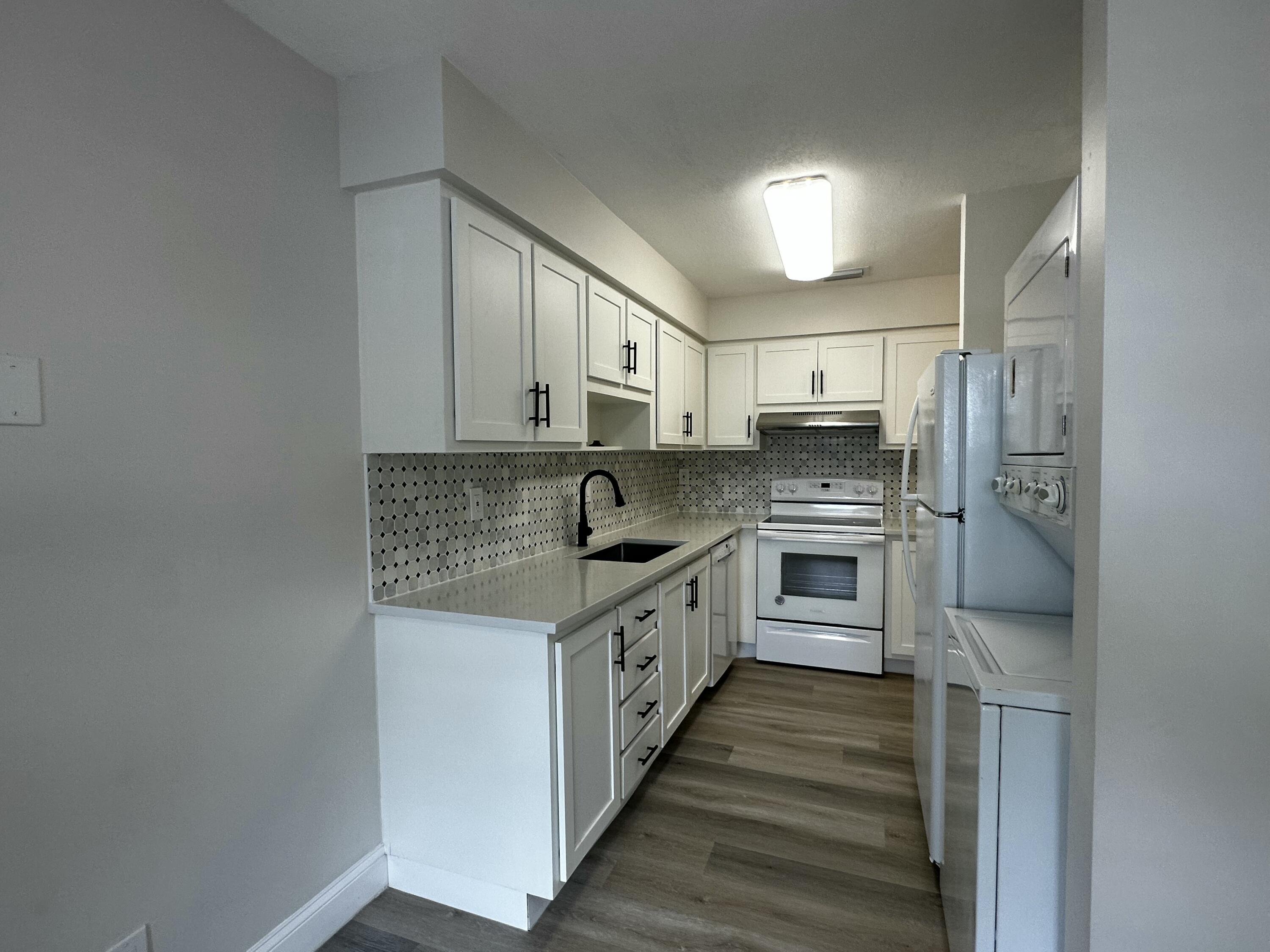 13682 Vía Flora, Unit H Delray Beach, FL 33484 - Photo 7 of 28 a kitchen with stainless steel appliances granite countertop a stove and a refrigerator