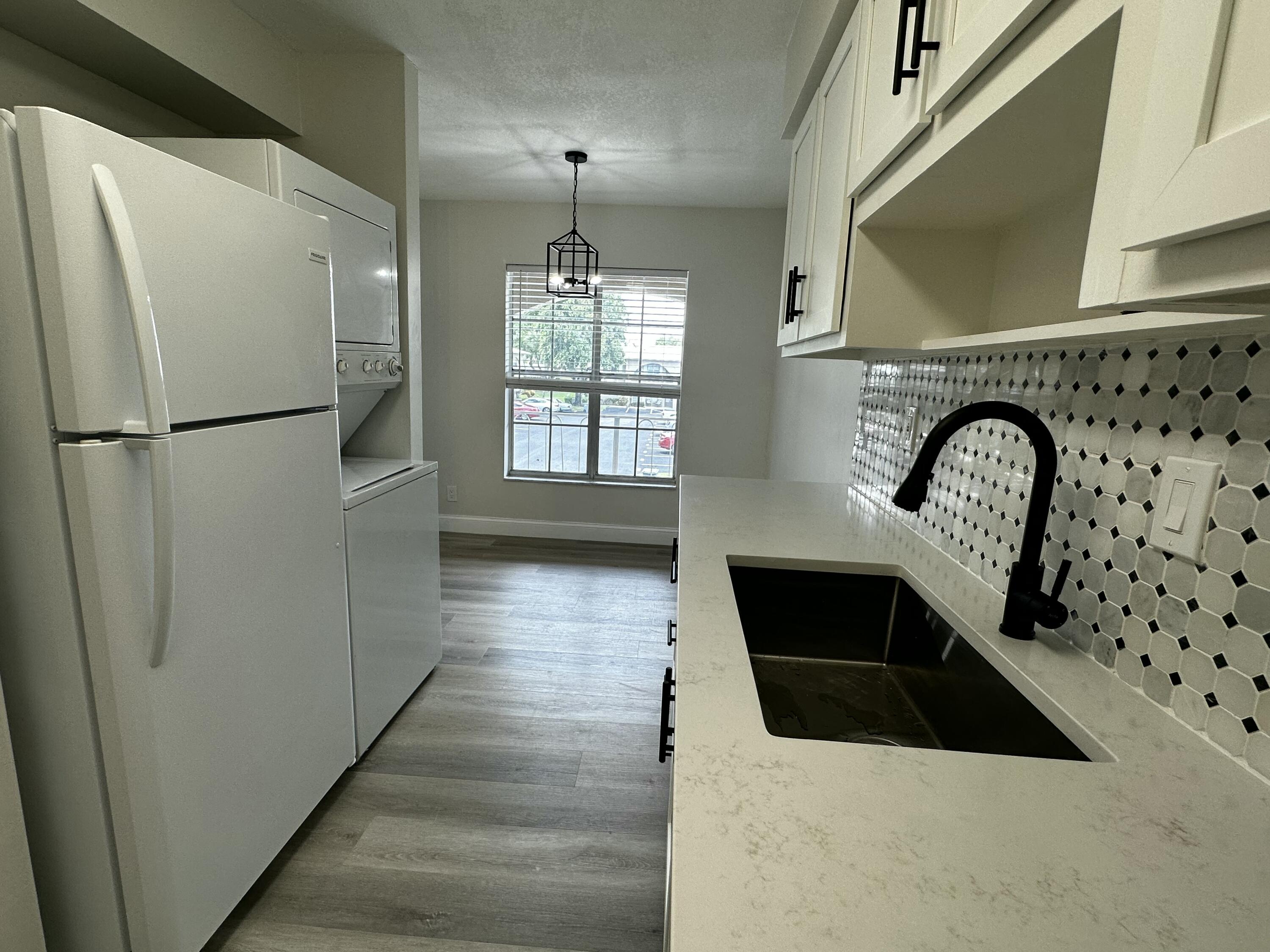13682 Vía Flora, Unit H Delray Beach, FL 33484 - Photo 9 of 28 a kitchen with granite countertop a refrigerator a sink and wooden floor