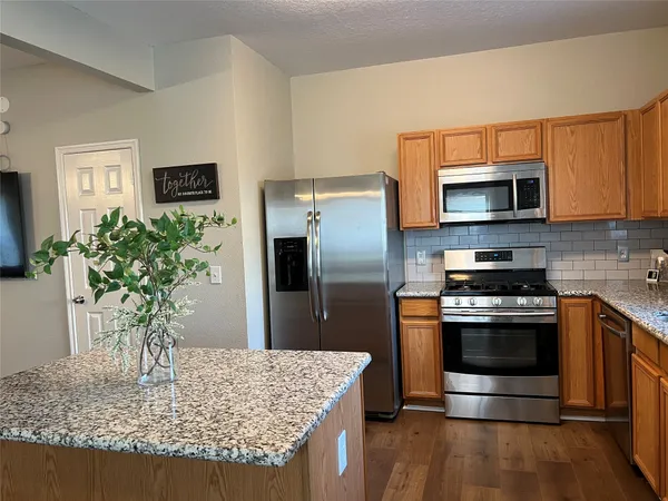 a kitchen with stainless steel appliances granite countertop a stove a microwave a sink and a refrigerator