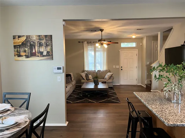 a kitchen with stainless steel appliances granite countertop a dining table chairs and a refrigerator