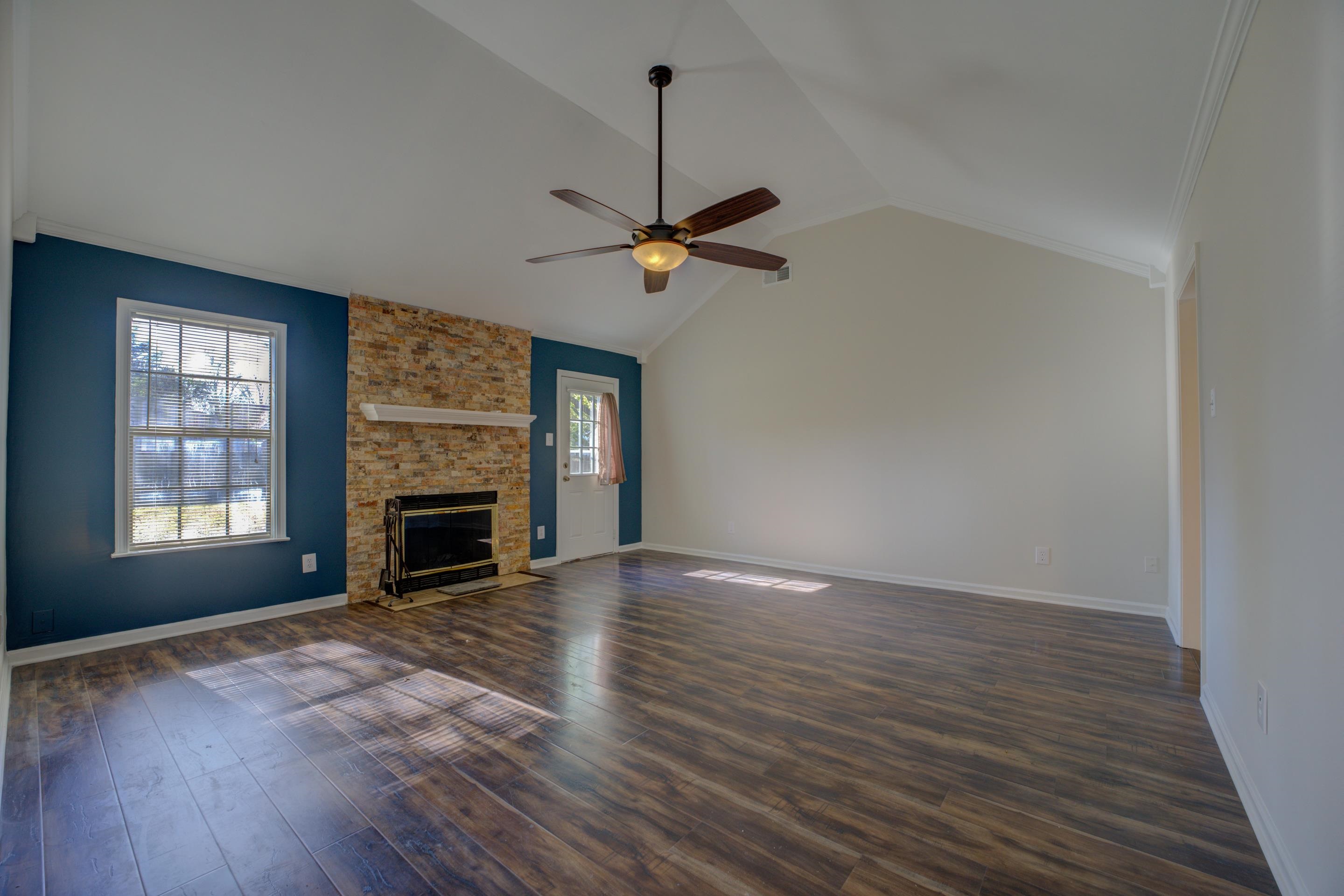 7555 Reese Road Memphis, TN 38133 - Photo 4 of 22 Unfurnished living room featuring ceiling fan, a stone fireplace, dark hardwood / wood-style flooring, high vaulted ceiling, and ornamental molding