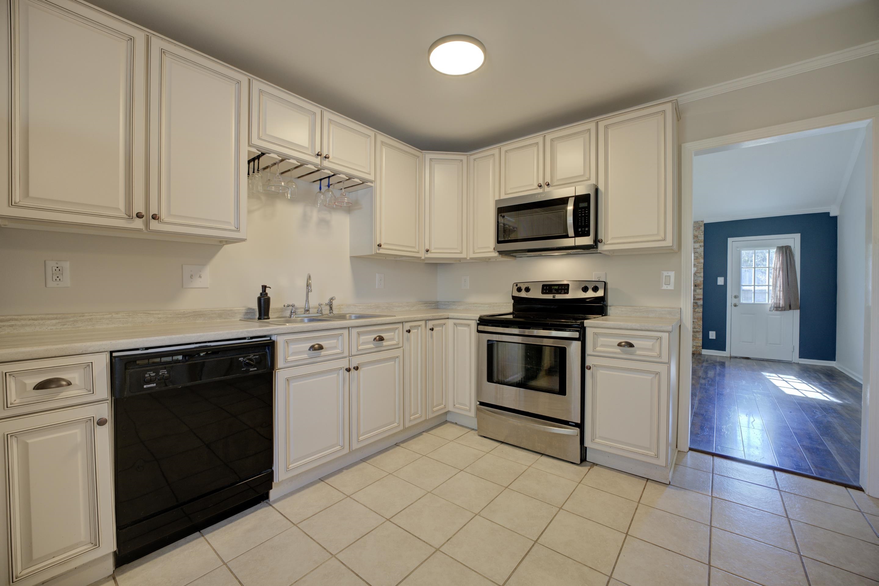 7555 Reese Road Memphis, TN 38133 - Photo 9 of 22 Kitchen featuring white cabinetry, sink, stainless steel appliances, crown molding, and light tile patterned flooring