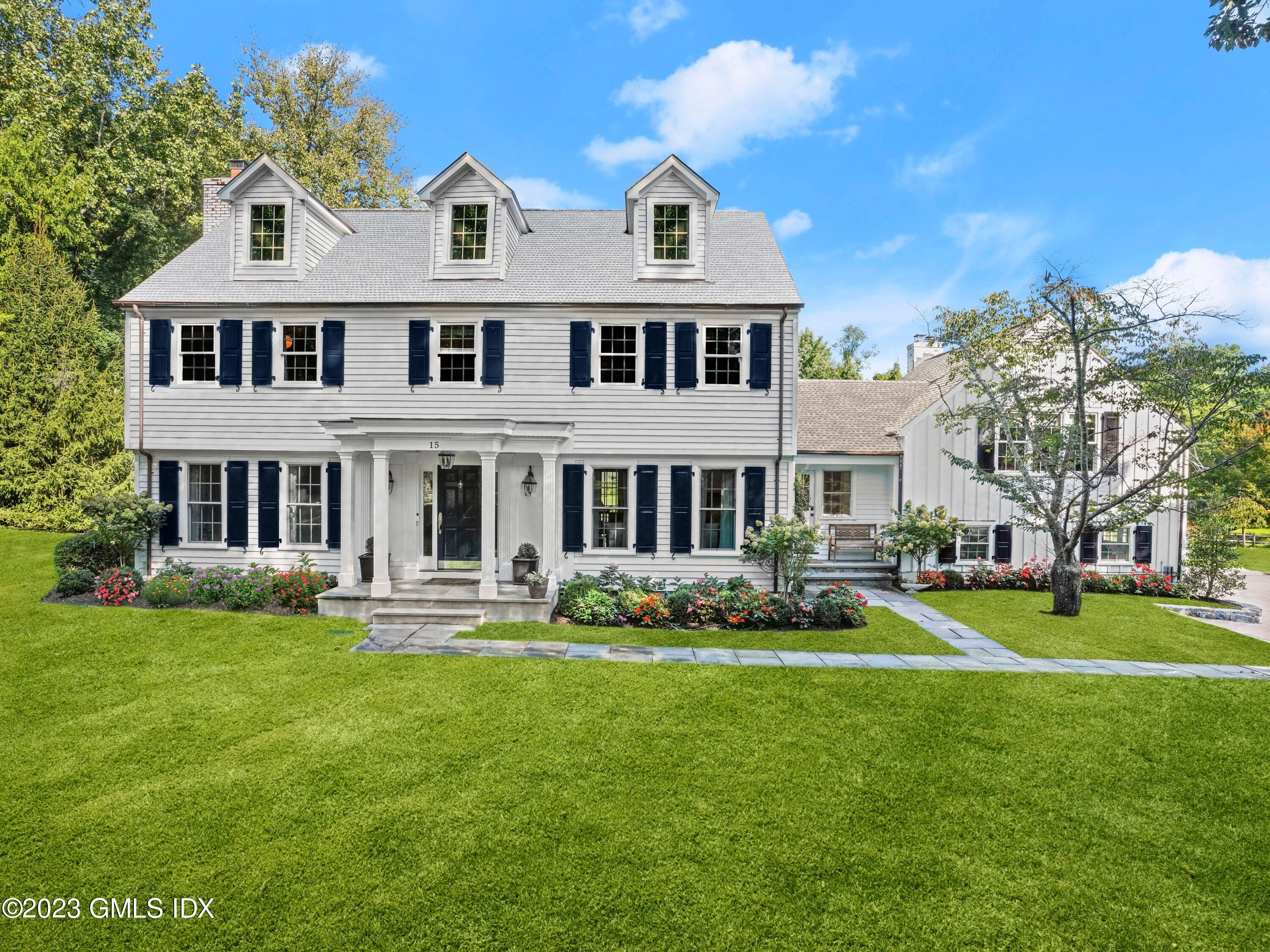 a front view of a house with garden and trees