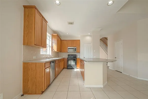 a large kitchen with stainless steel appliances a sink and cabinets