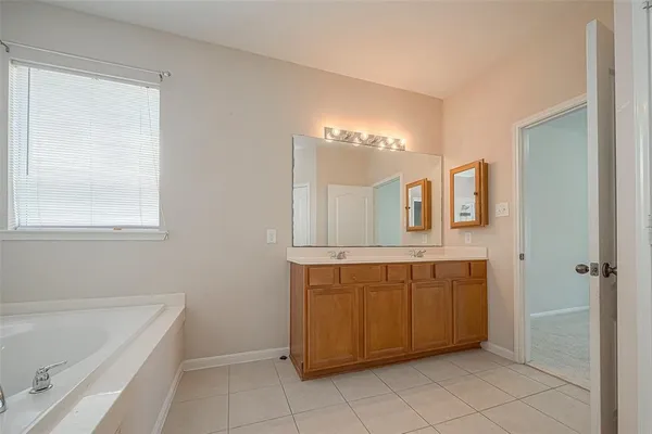 a spacious bathroom with a mirror a bathtub and a sink