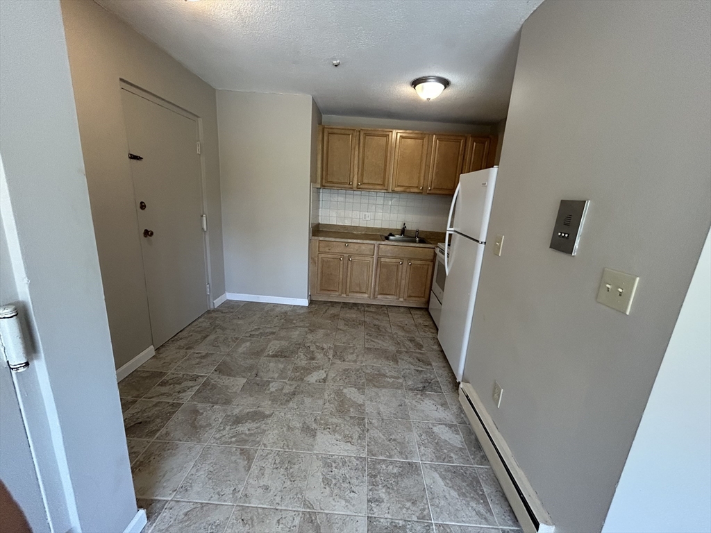 71 Pond Street, Unit 21A Quincy, MA 02169 - Photo 4 of 9 a view of a refrigerator in kitchen and wooden floor