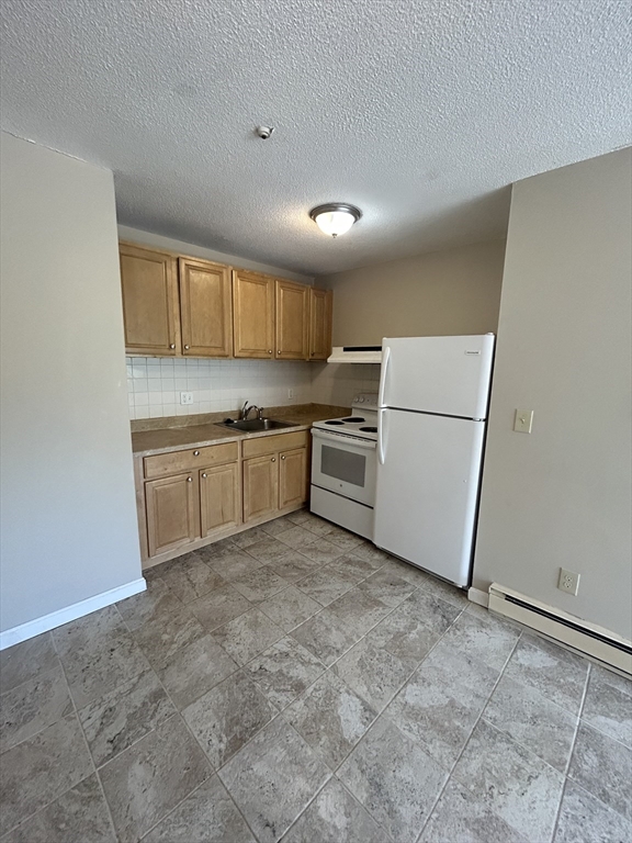 71 Pond Street, Unit 21A Quincy, MA 02169 - Photo 5 of 9 a kitchen with white cabinets and white appliances