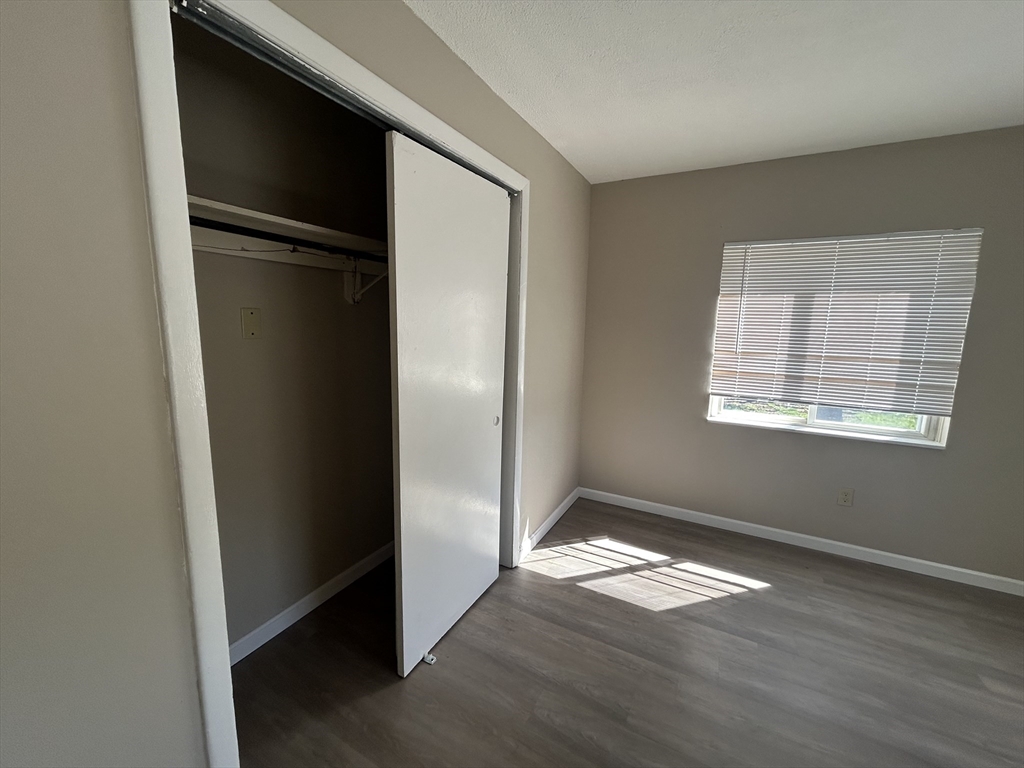 71 Pond Street, Unit 21A Quincy, MA 02169 - Photo 7 of 9 an empty room with wooden floor cabinet and windows